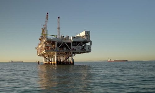 Off the coast of Long Beach, California, an imposing offshore drilling rig rises from the waves, a towering structure of steel and machinery. The rig is a hive of activity, with workers toiling around the clock to extract oil and gas from beneath the ocean floor. The sound of heavy machinery fills the air, and the smell of petroleum lingers on the sea breeze.The rig is a marvel of engineering, with massive cranes and drills capable of reaching depths of thousands of feet below the surface. It is a symbol of America's reliance on fossil fuels, and the risks and rewards that come with offshore drilling.Despite its imposing size, the rig is a small speck in the vastness of the ocean, and its impact on the surrounding ecosystem is a matter of ongoing debate. Proponents argue that the benefits of domestic energy production outweigh the potential environmental risks, while opponents point to the dangers of oil spills and the long-term impact on marine life.As the sun sets on the horizon, the rig continues to churn away, a reminder of the complex and often contentious relationship between humans and the natural world.